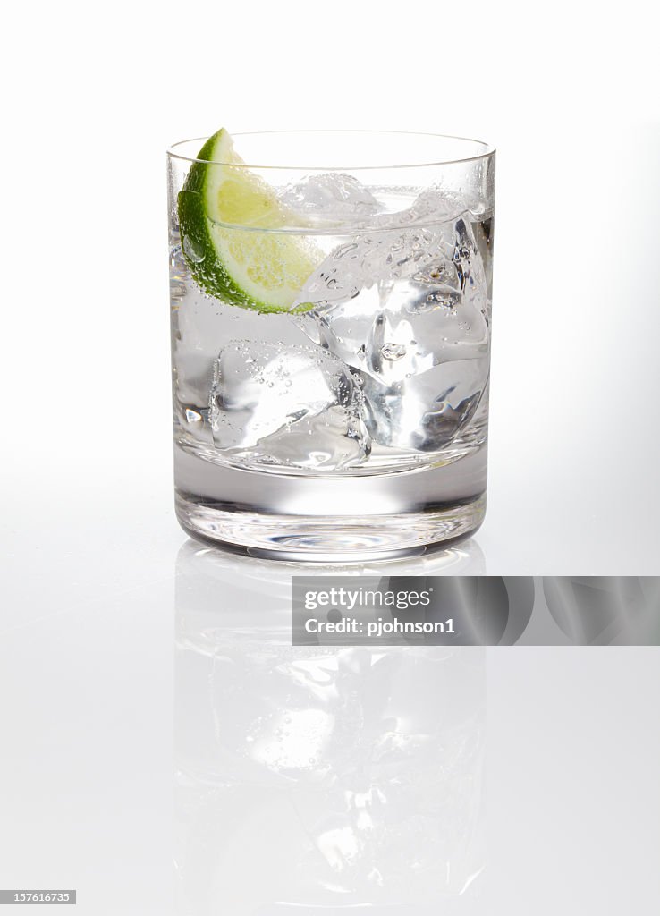 A glass of gin and tonic with ice and a slice of lime 