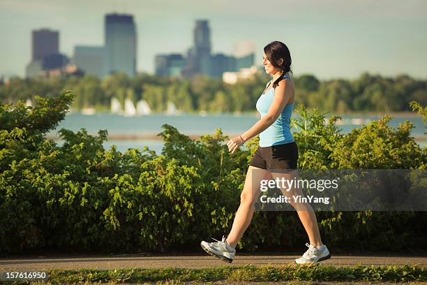 woman exercise power walking in urban city park, minneapolis, minnesota - minneapolis lake stock pictures, royalty-free photos & images
