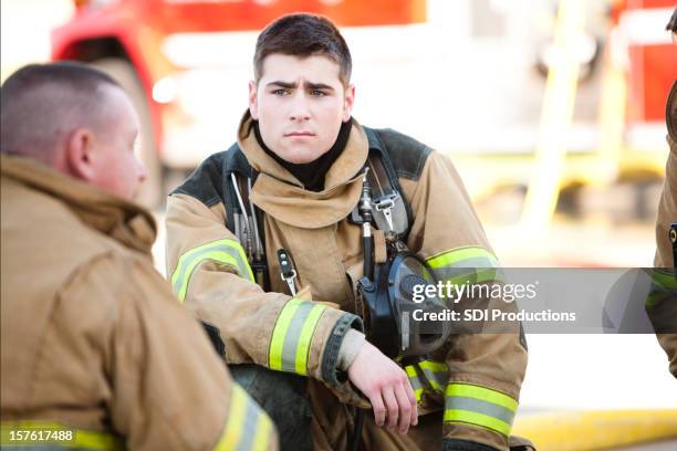 young firefighters discussing fire fighting issues with each other - firefighter stock pictures, royalty-free photos & images