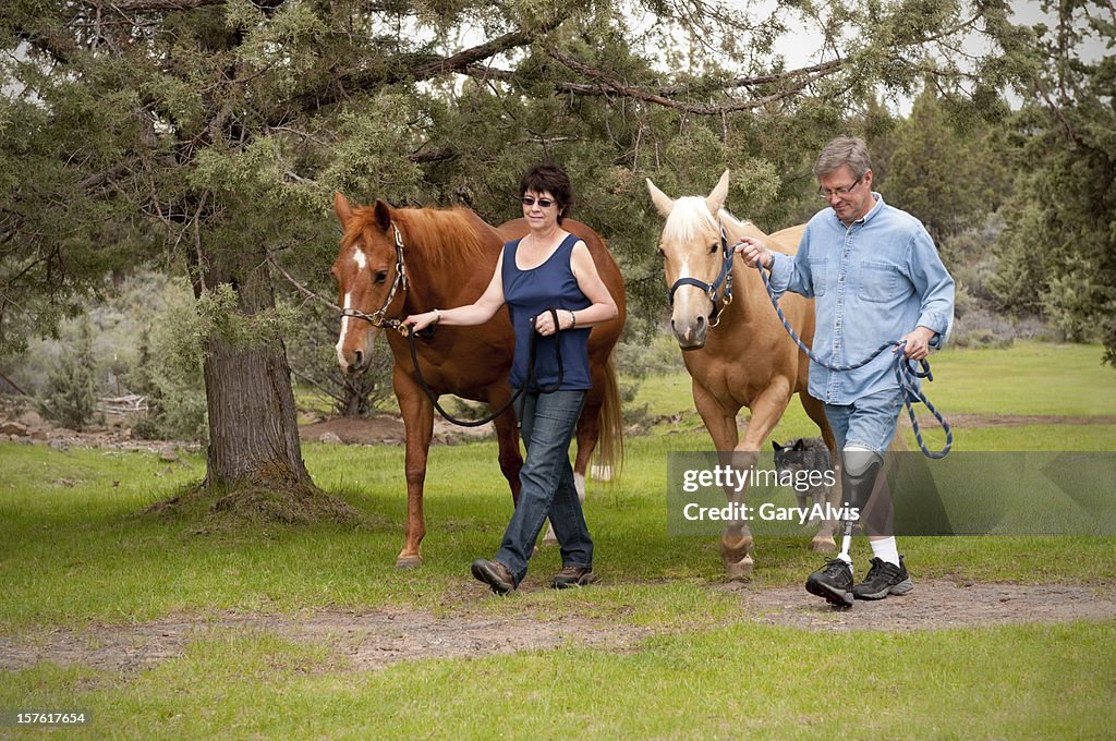 Amputee w/wife, leading horses down a path