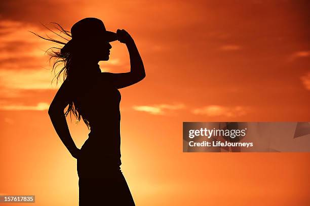 cowgirl silhouette in einem warmen orangen western sky - cowgirl stock-fotos und bilder