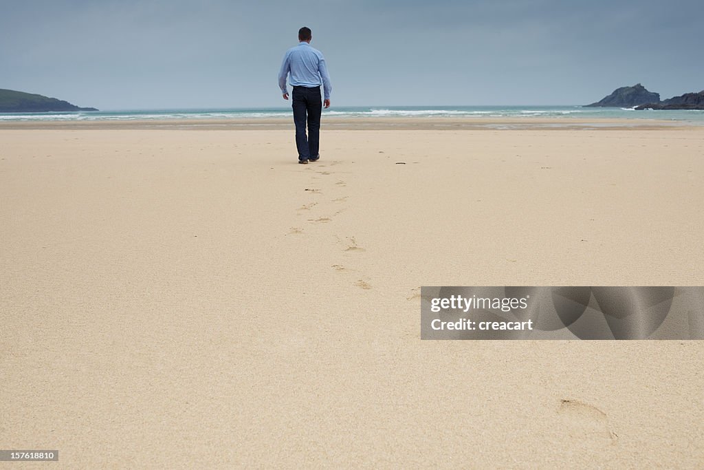 Lone man walking on a deserted beach