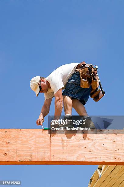 construction worker using a speed square on laminated lumber beams - construction danger stock pictures, royalty-free photos & images