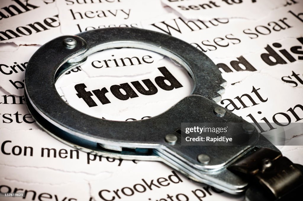 Handcuffs over newspaper with the word fraud