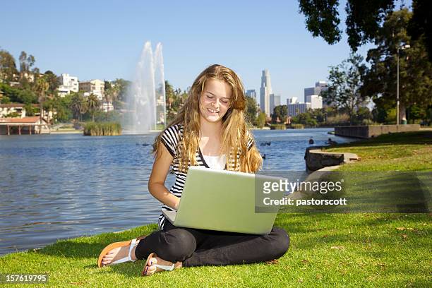 ragazza sorridente sul computer portatile nel parco all'aperto di los angeles - wap foto e immagini stock