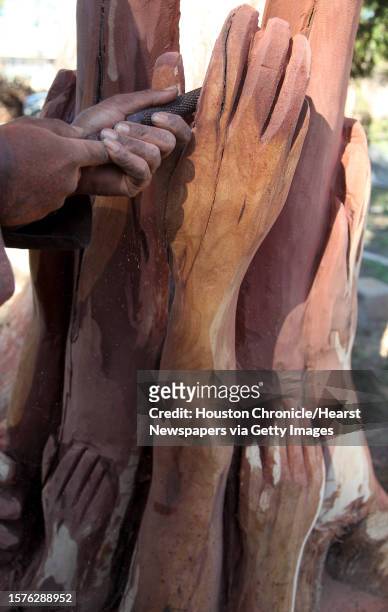 Sculptor Earl Jones give more definition to the hands carved in his tree sculpture at the historic African American College Park Cemetery on Friday,...