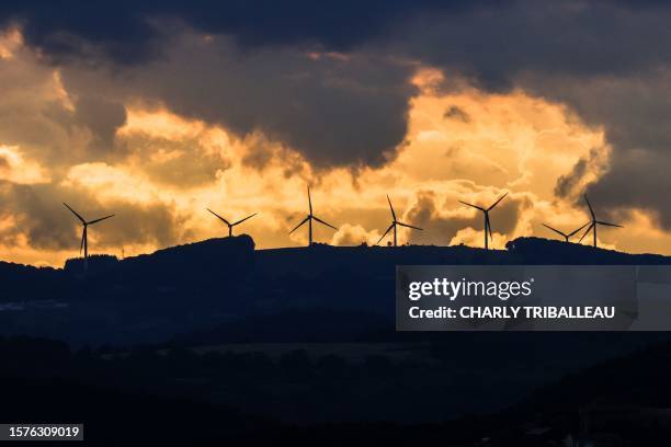 Wind turbines are pictured at sunset on a hill near Roquefort-sur-Soulzon, southern France, on August 1, 2023.