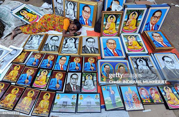 Woman naps amidst photo frames with images of the architect of the Indian constitution, Bhim Rao Ambedkar and Lord Gautam Buddha on the eve of...