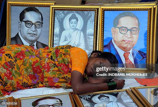 Woman naps amidst photo frames with images of the architect of the Indian constitution, Bhim Rao Ambedkar and Lord Gautam Buddha on the eve of...