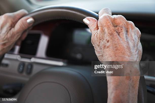 senior woman hands on steering wheel - lentigo stockfoto's en -beelden