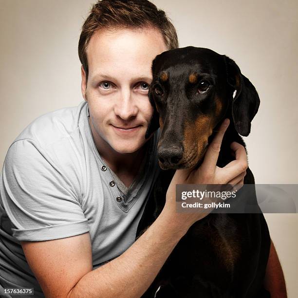 man hugging doberman pinscher - dog sitting stock pictures, royalty-free photos & images