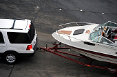 White SUV pulling white speed boat on trailer from above