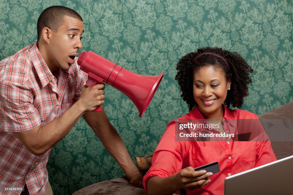 Man using megaphone as woman shops online at home