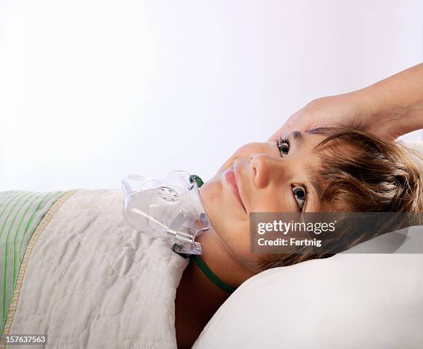 lächelnd kleiner junge mit einer sauerstoff-maske im krankenhaus - narkosemittel stock-fotos und bilder