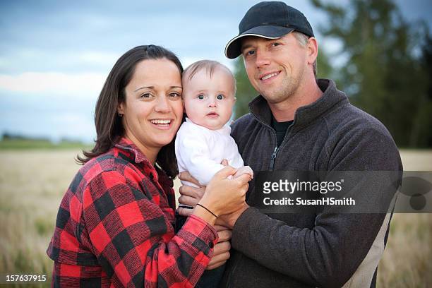 a mother and father holding their baby in a field - blue collar worker family stock pictures, royalty-free photos & images