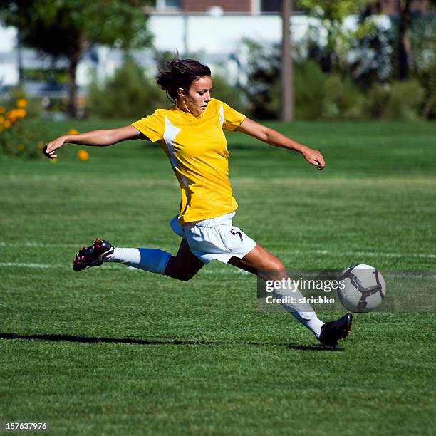 female soccer player in yellow jumps to touch bouncing ball - womens football stock pictures, royalty-free photos & images