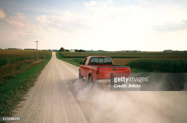 red pick up truck traveling down a dusty midwest road. - truck stock pictures, royalty-free photos & images