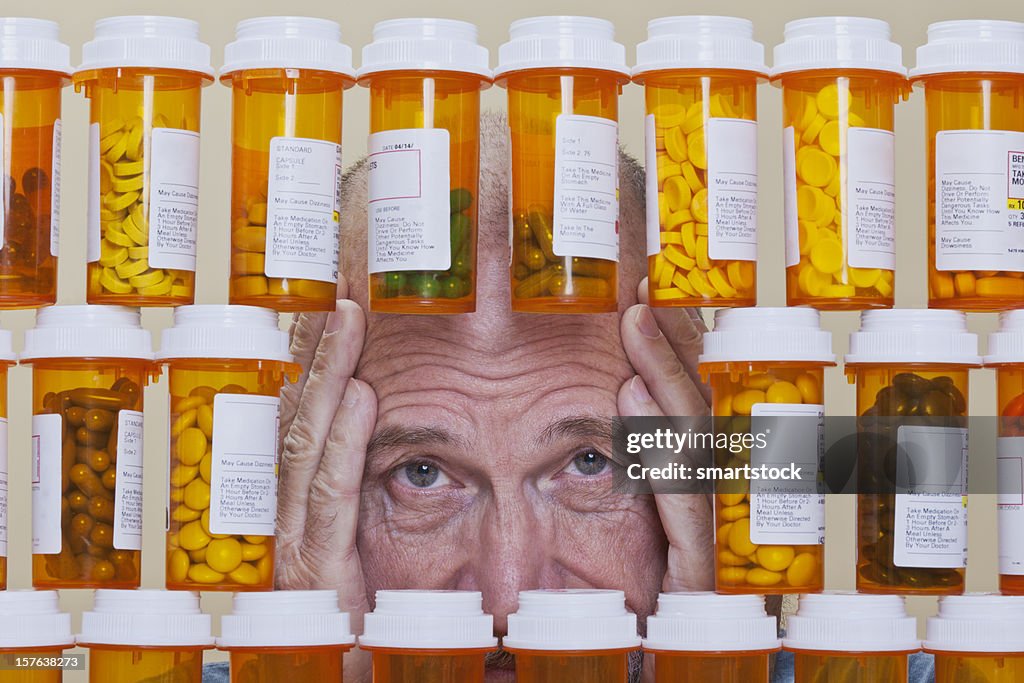 Depressed Senior Man Looking Through Rows of Prescription Medication
