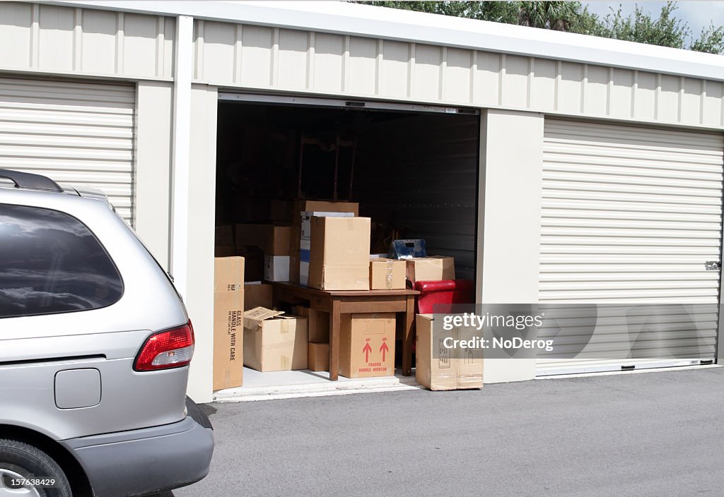 An open self storage unit with a van parked next to it