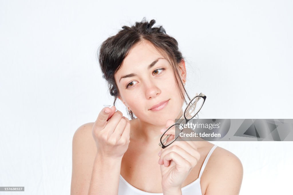 Girl holding glasses in one hand and contact lens other hand