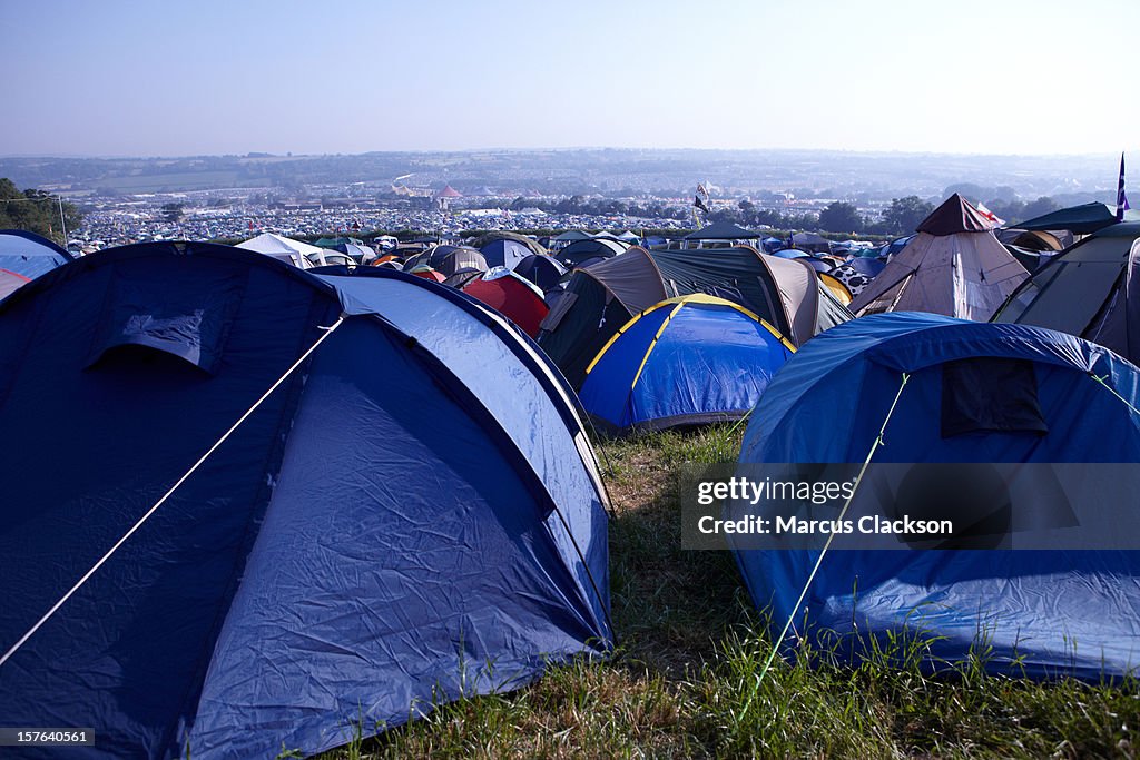 Tents crowded together on a grassy hill for a festival