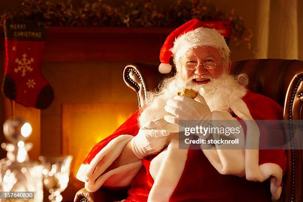 father christmas enjoying a mince pie by the fire - sitting by fireplace stock pictures, royalty-free photos & images
