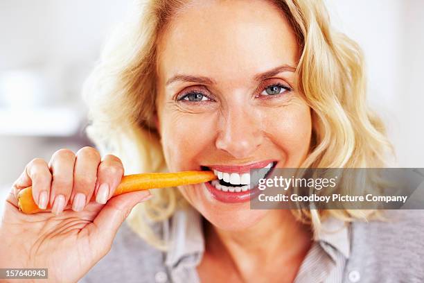 glückliche ältere frau isst a carrot-englische redewendung - woman teeth stock-fotos und bilder