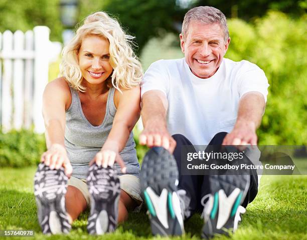 senior couple ausübung im park - zehenspitzen berühren stock-fotos und bilder