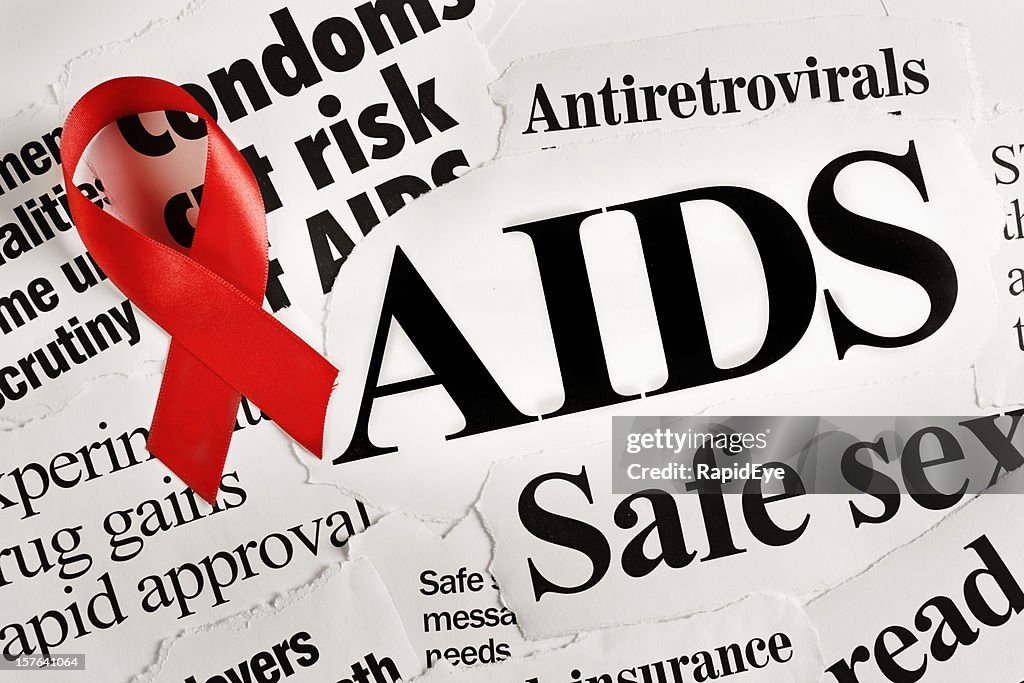 Red AIDS ribbon on headlines concerning the disease