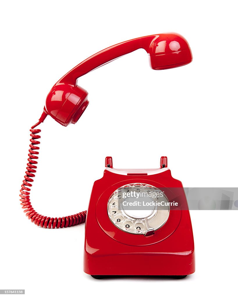 Red rotary dial telephone with cord on white background