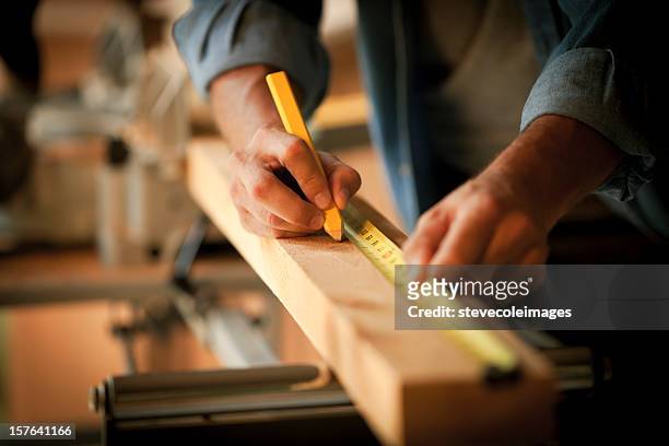 carpenter measuring a wooden plank - hands at work stockfoto's en -beelden