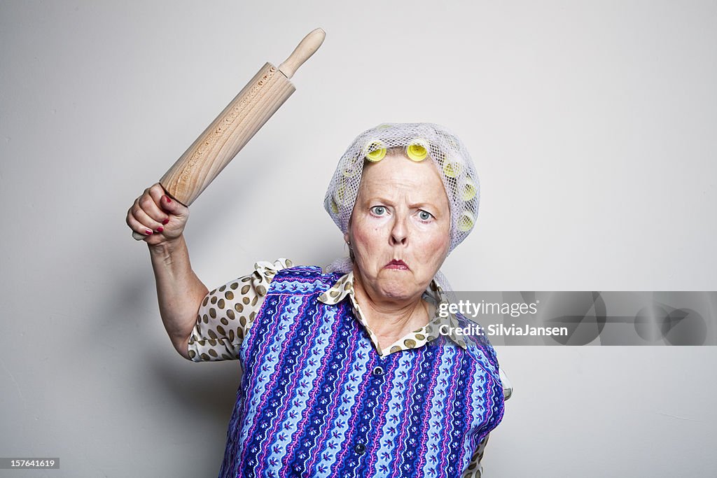 Angry retro senior housewife with rolling pin