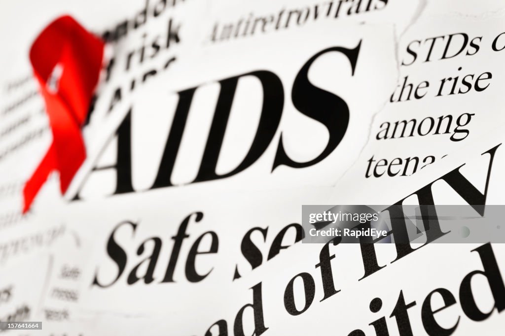 Red awareness ribbon on AIDS related newspaper headlines