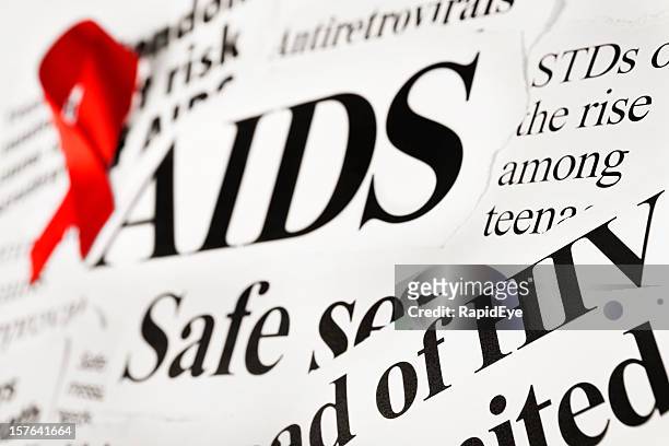 red awareness ribbon on aids related newspaper headlines - aids epidemic stock pictures, royalty-free photos & images