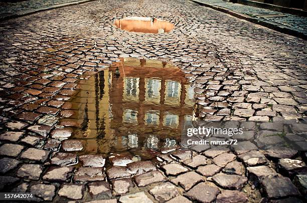 cobblestone with water puddle - cobblestone puddle stock pictures, royalty-free photos & images