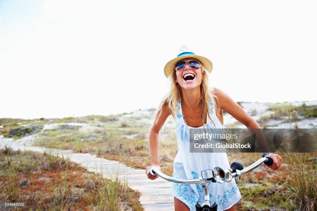 Happy woman cycling on wooden track at beach