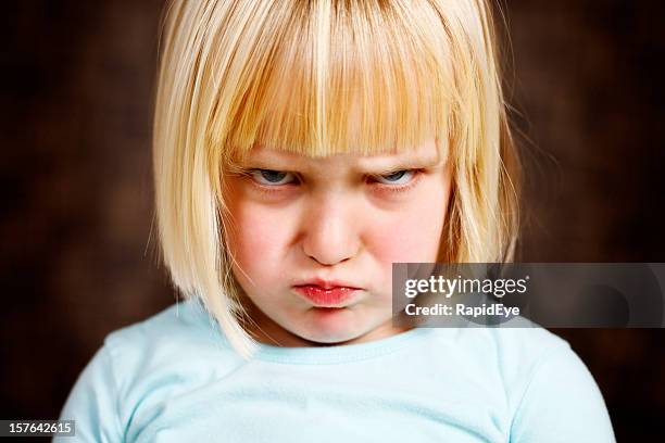 cute blonde toddler girl scowls at camera - sulking stockfoto's en -beelden