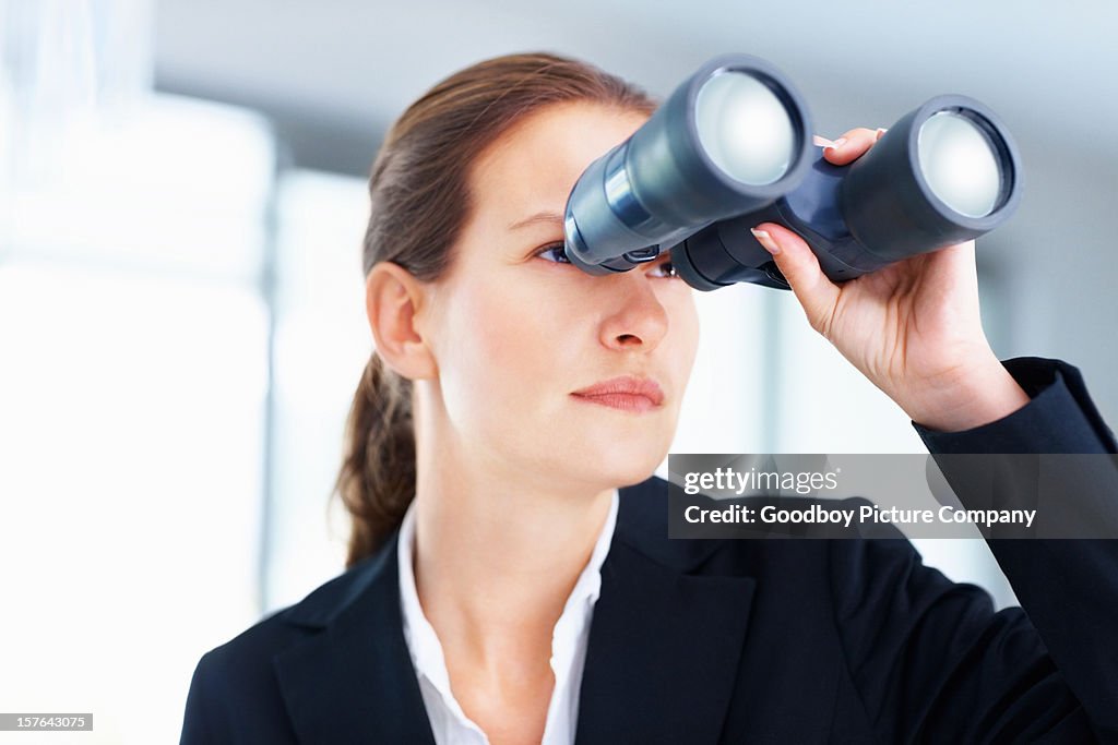 Beautiful business woman looking through binoculars