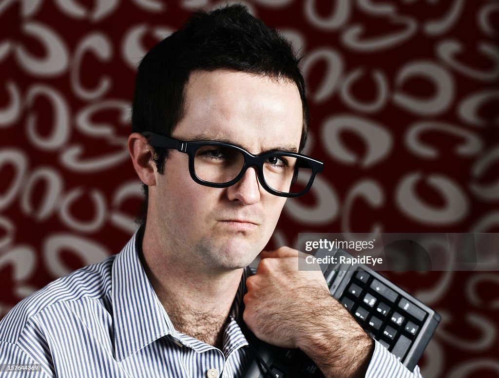 Young IT geek clutches his keyboard and scowls