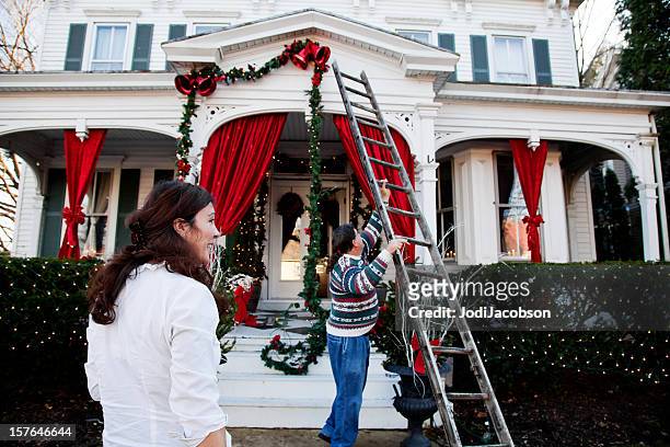 middle aged couple decorating for the holidays - hanging stock pictures, royalty-free photos & images