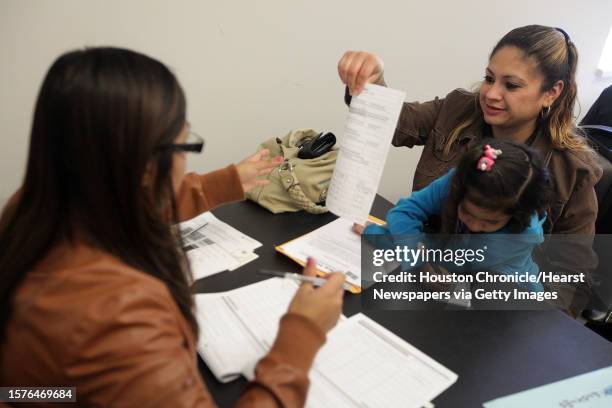 Angelica Mejia holds daughter Breanna Mejia as she receives help in filling out the citizenship form correctly during a citizenship and immigration...