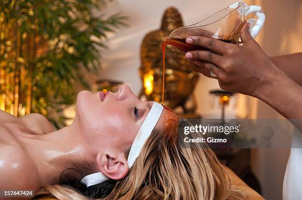 a woman has a soothing ayurveda massage to her forehead  - shirodhara stock pictures, royalty-free photos & images