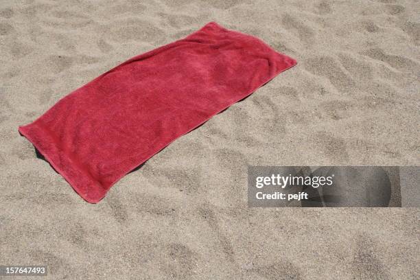 red towel left on sandy beach - towel stockfoto's en -beelden