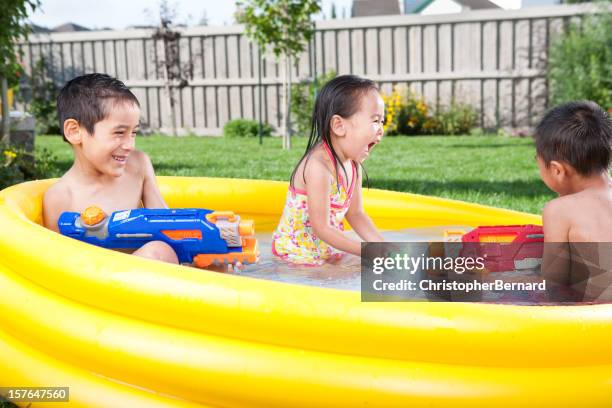 kids swimming in wading pool - waterpistool stockfoto's en -beelden