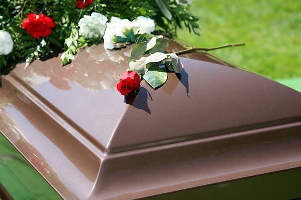 wooden color casket with flowers and a rose on top - funeral stock pictures, royalty-free photos & images