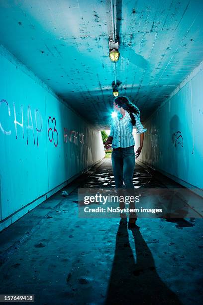 running girl looking backwards in tunnel - ontsnappen stockfoto's en -beelden