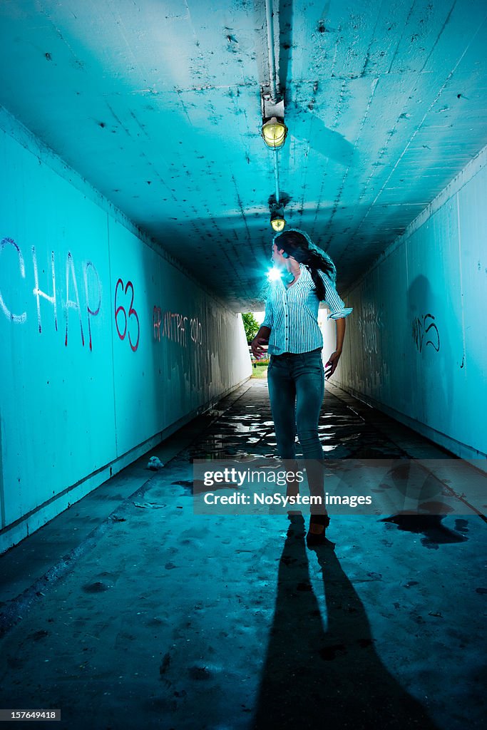 Running girl looking backwards in tunnel