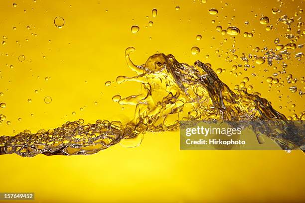 a splash of water over a yellow background - oil splashing stock pictures, royalty-free photos & images