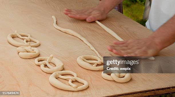 pretzel making hands roll raw dough wooden table close up - pretzel stockfoto's en -beelden