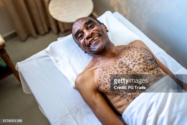 portrait d’un homme âgé sur une table de massage dans un hôtel - banc de massage photos et images de collection